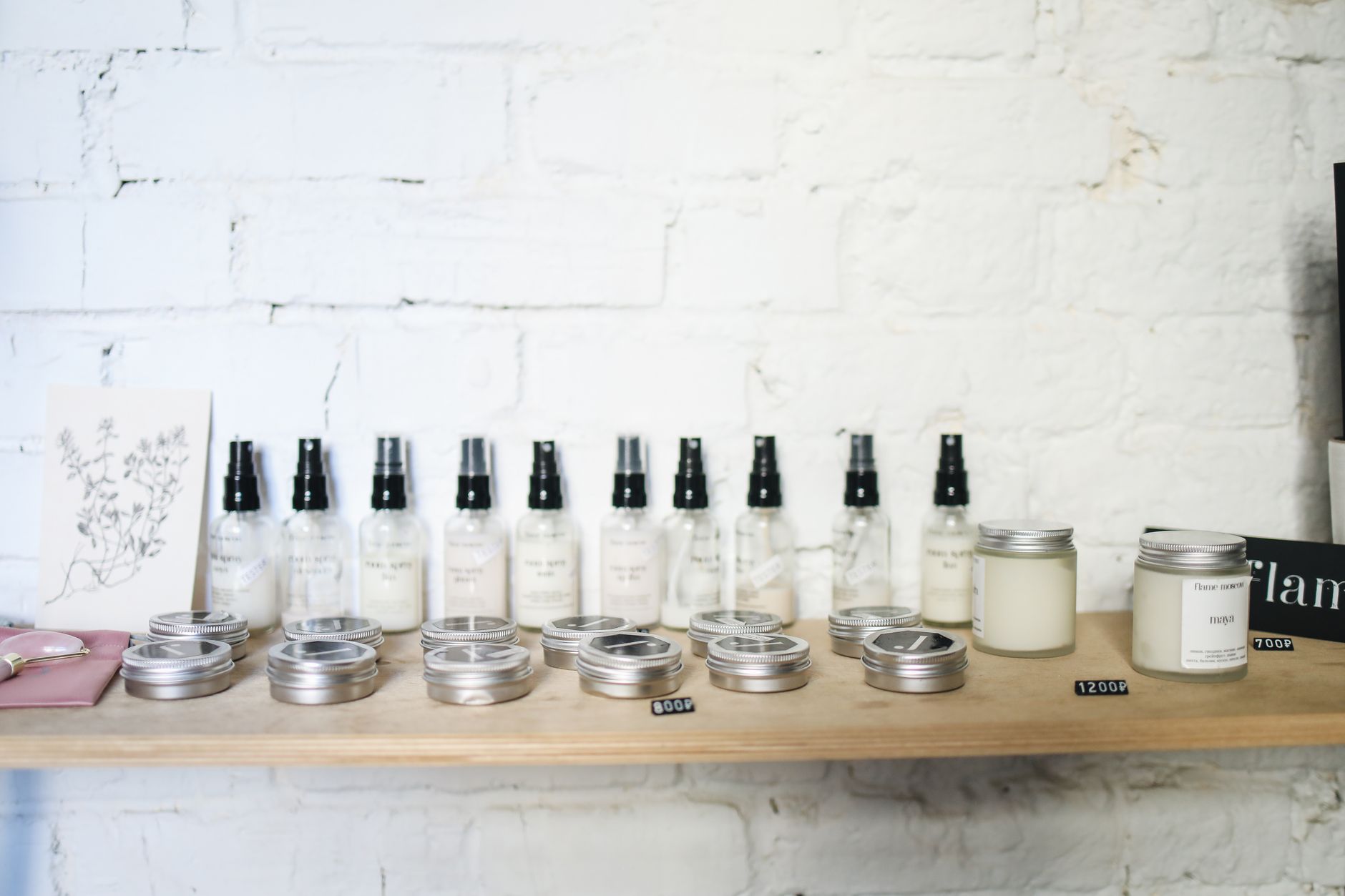Skincare bottles and jars arranged on a retail shelf against a white brick wall
